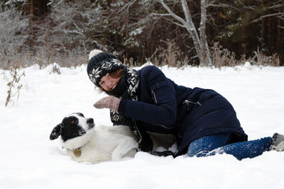 Rear view of person with dog on snow