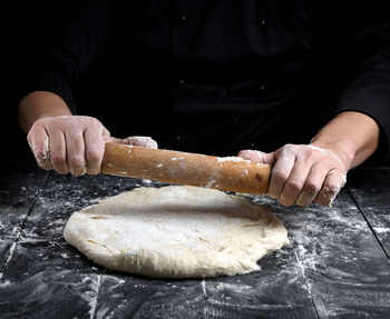 Midsection of chef rolling dough at table