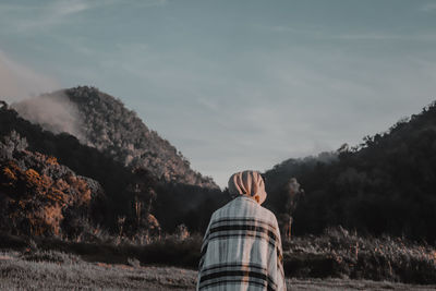 Rear view of woman sitting on land against forest