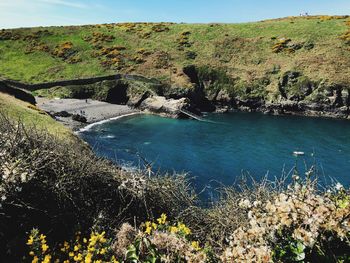 Scenic view of river by cliff against sky