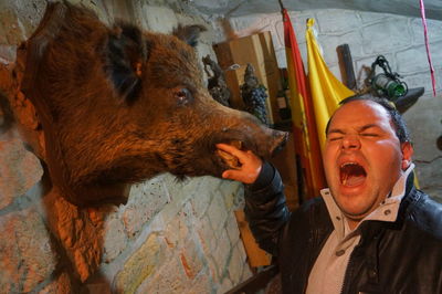 Mischievous man putting hand in mouth of dead boar