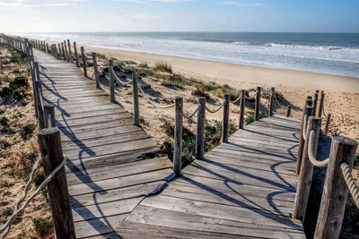 Wooden posts on beach against sky