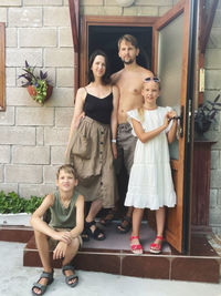 Portrait of family standing next to their house