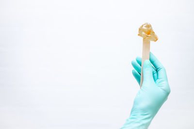 Close-up of hand holding ice cream over white background