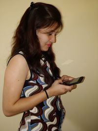 Young woman using mobile phone by wall at home