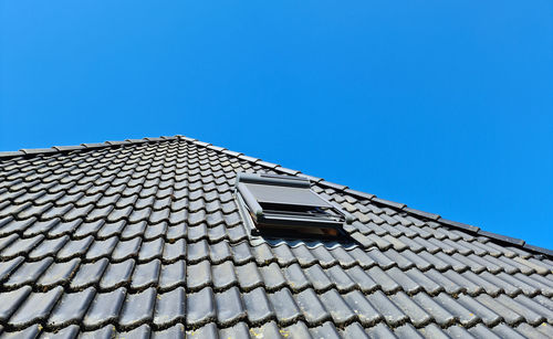 Open roof window in velux style with black roof tiles