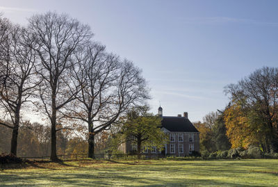 Trees and houses on field against sky