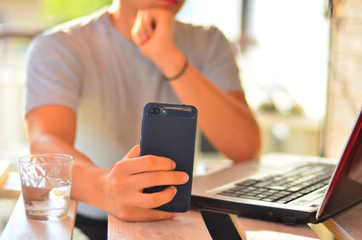 Midsection of man using mobile phone on table