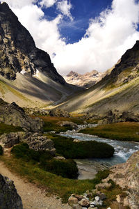 Scenic view of river by mountains against sky