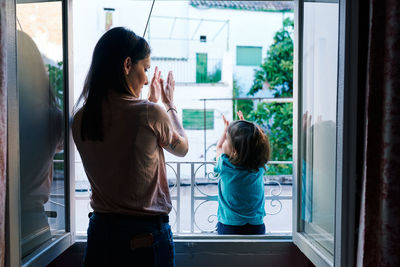 Rear view of women standing in glass window