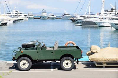 Sailboats  and vehicle moored at harbor against sky