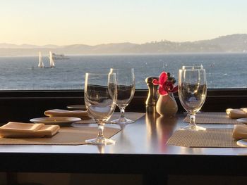 Close-up of wine glasses on table against clear sky