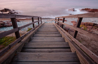 Boardwalk leading towards footbridge against sky