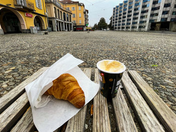 Coffee cup on table against buildings in city