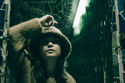 Portrait of confident young woman wearing hood in illuminated restaurant