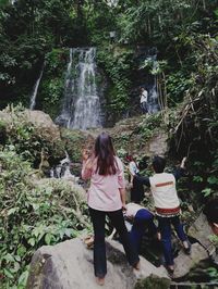 Rear view of people standing in forest