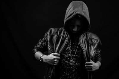 Young woman wearing mask against black background