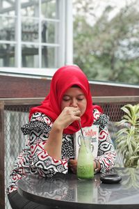 Woman drinking while sitting at restaurant