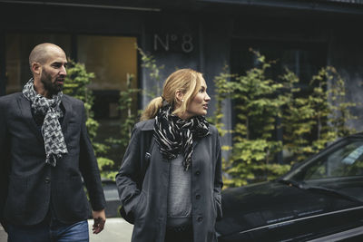 Mid adult businessman and businesswoman crossing city street