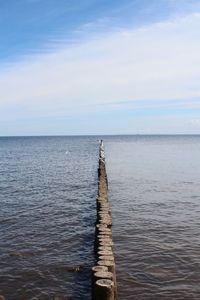 Wooden posts in sea against sky