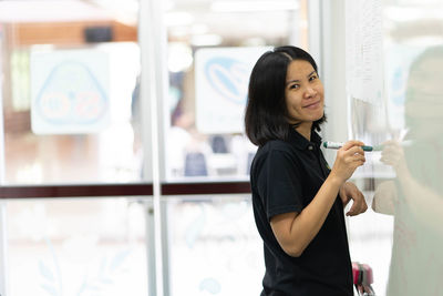 Portrait of smiling businesswoman standing by whiteboard in office