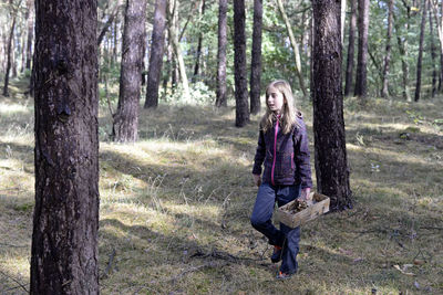 Cute girl with container walking in forest