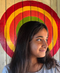 Portrait of young woman standing against wall