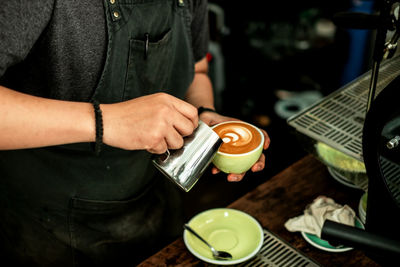 Midsection of man holding coffee cup on table