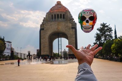 Midsection of person holding umbrella against sky in city