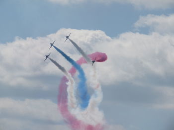 Low angle view of air show against cloudy sky