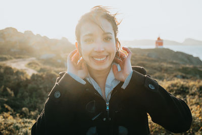 Portrait of young woman standing against mountain