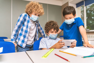 Boys wearing mask playing on mobile phone