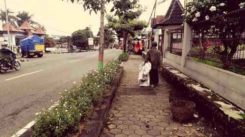 Rear view of people walking on street in city