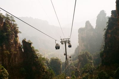 Low angle view of overhead cable cars against sky