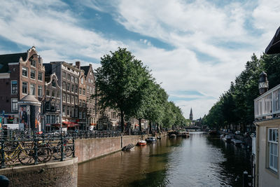 Canal passing through city against sky