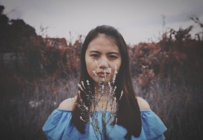 Portrait of beautiful woman with plant standing outdoors