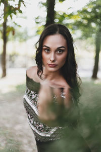 Portrait of woman standing against tree