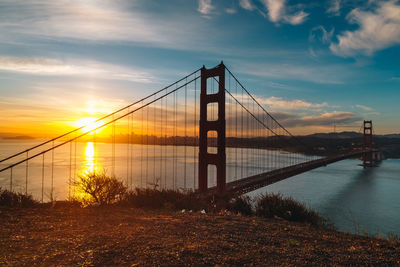 Bridge over river against sky during sunset