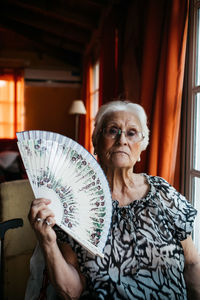 Portrait of old woman sitting holding a fan