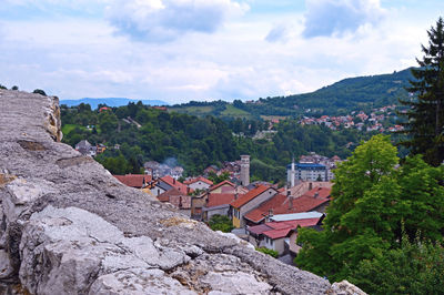 Houses by trees and buildings against sky