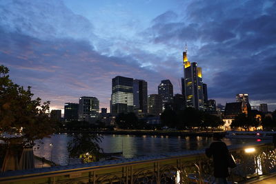 Illuminated buildings in city against cloudy sky