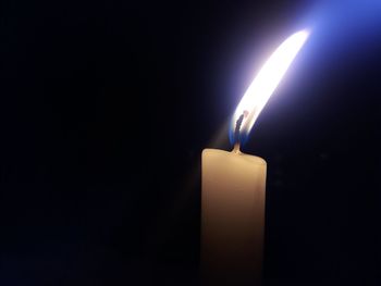 Close-up of candle burning against black background