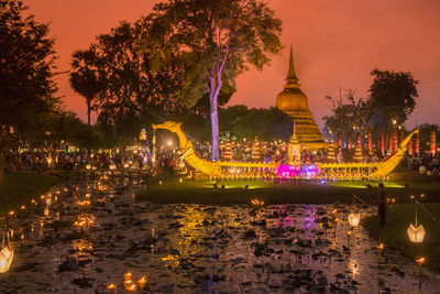 Illuminated building by lake at night