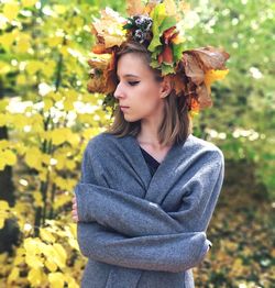 Beautiful woman wearing wreath while standing against plant