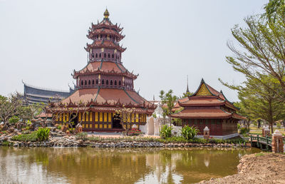 Temple by lake and buildings against sky