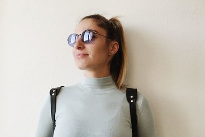 Portrait of young woman looking away against wall