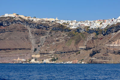 Scenic view of sea and mountains against clear blue sky