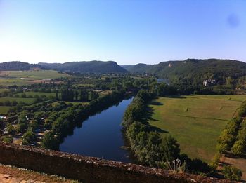 Scenic view of landscape and river against clear blue sky