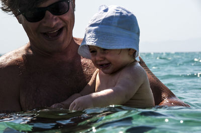 Close-up of father and daughter swimming in sea against sky