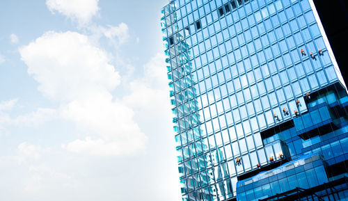 Low angle view of modern glass building against sky